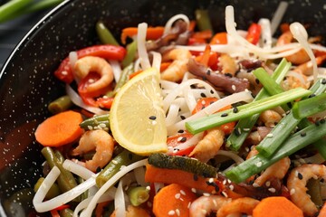 Shrimp stir fry with noodles and vegetables in wok, closeup