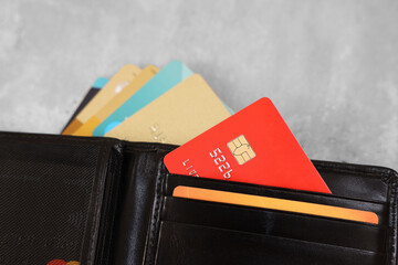 Many different credit cards and leather wallet on grey table, closeup