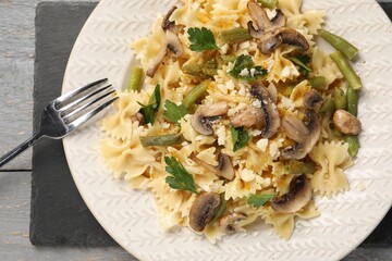 Vegetarian pasta with mushrooms, parsley, string beans and cheese on grey wooden table, top view