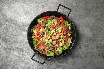 Stir fried noodles with mushrooms and vegetables in wok on grey table, top view