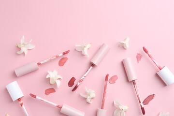 Different lip glosses, applicators and flowers on pink background, flat lay. Space for text - obrazy, fototapety, plakaty