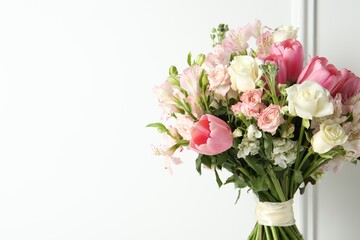 Beautiful bouquet of fresh flowers near white wall. Space for text