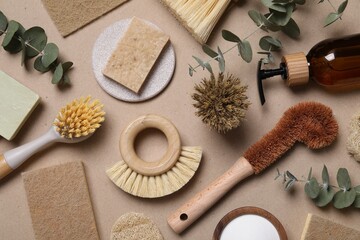 Cleaning brushes, baking soda, soap, sponges and eucalyptus leaves on pale brown background, flat...