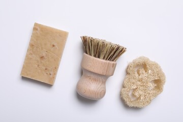 Cleaning brush, soap bar and loofah on white background, flat lay