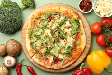 Delicious vegetarian pizza and products on green table, flat lay