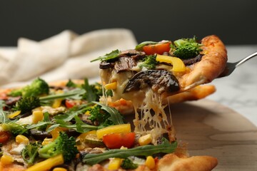 Taking piece of delicious vegetarian pizza at table, closeup