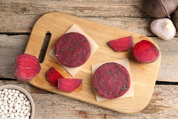 Vegetarian product. Uncooked beetroot cutlets and ingredients on wooden table, top view