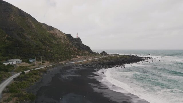 A black beach coastline and a lighthouse in New Zealand