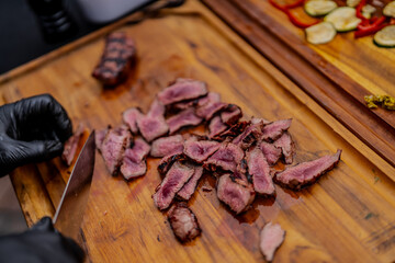 Pink cut steak peaces on wooden cutting board after grilling in the summer picnic time, cooked to a perfection as medium rare pieces