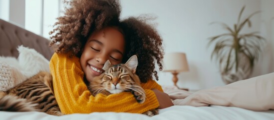 A little girl tenderly hugs her kitten and lies on the bed in the morning in a bright bedroom. Friendship concept between child and pet, copy space for text, banner
 - obrazy, fototapety, plakaty