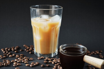 Glass of Frappuccino with ice and glass coffee scoop on dark background