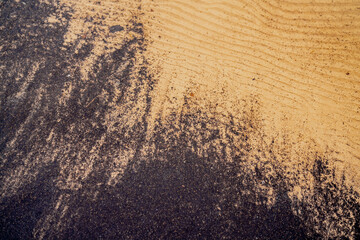 Black mud flowing in the water of yellow sea sand. Mixing good and bad in nature