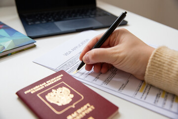 Close up of female hand filing out a visa application with a Russian passport