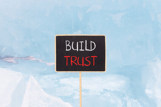 Build trust symbol. Concept words Build trust on beautiful yellow black blackboard. Beautiful blue ice background. Business and build trust concept, copy space.