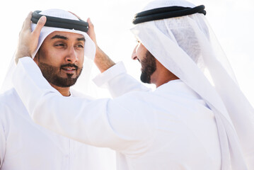 Two arab men wearing traditional emirati clothing in the desert of Dubai - Middle-eastern adult...