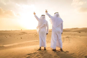 Foto op Canvas Two arab men wearing traditional emirati clothing in the desert of Dubai - Middle-eastern adult males portrait © oneinchpunch
