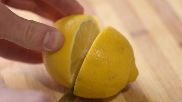 Cutting lemon in half on wooden table. Cooking with lemon juice, cutting it to squeeze