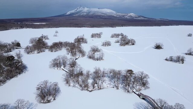 Lake Onuma, Japan: Aerial drone footage of the frozen lake Onuma with the Komagatake volcano in the background near Hakodate in Hokkaido in winter in Japan