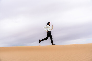 Beautiful arab sportive woman wearing hijab training outdoors in the desert