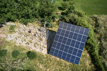 Workers installing solar panels in field at sunny day. Array as a system of photo-voltaic panels. Arrays of a solar panel system supplying solar electricity to electrical equipment.
