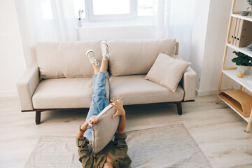 Relaxing in a Cozy Modern Apartment - Comfortable Sofa, Happy Woman Lying on the Floor, Enjoying a...