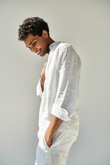 joyous alluring african american male model in white linen attire looking away on beige backdrop