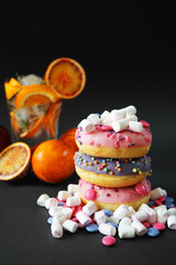 Several donuts with pink and purple glaze and sprinkles next to marshmallows and candies against a...
