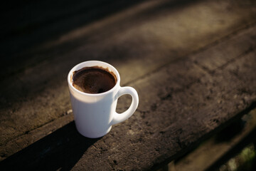 a cup of coffee stands on a wooden table in the garden