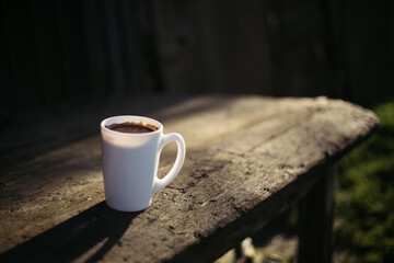 a cup of coffee stands on a wooden table in the garden