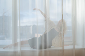 Caucasian woman dancing modern dance on the windowsill. 