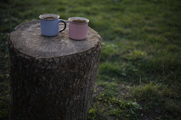 a cup of coffee stands on a wooden table in the garden