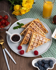Golden Triangle Waffles Breakfast with Berries and Fresh Orange Juice on Gingham Table Setting