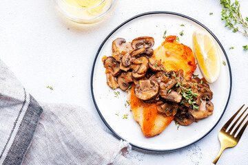French breaded chicken breast steak with mushrooms and onion sauce with white wine and thyme on plate, white  table background, top view - 783074751