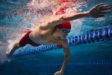 Freestyle swimming type. Dynamic image of yo9ung male athlete, swimmer in motion, training in...
