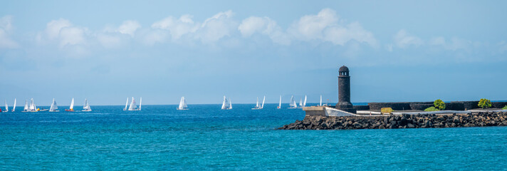 Regatta past the lighthouse at the entrance of the Arrecife harbor, Lanzarote, Canary Islands, Spain