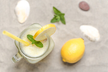 Fresh lemonade in glass jar on sand beach. Refreshing lemon drink, top view. - 783081334