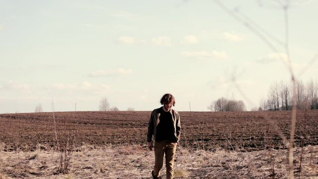 man with long hair in a brown leather jacket walks through a field in depression, existential crisis, midlife crisis