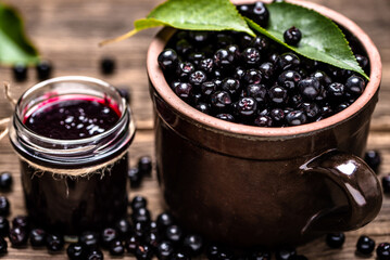 Aronia jam and fresh berry on wooden table.