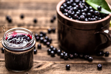 Aronia jam and fresh berry on wooden table.