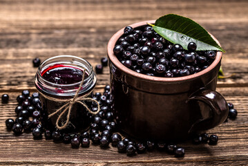 Aronia jam and fresh berry on wooden table. - 783082101