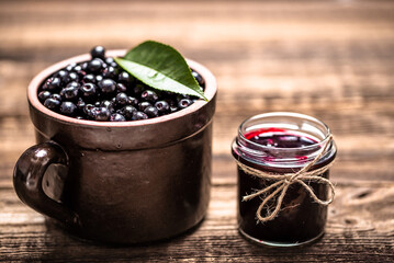 Aronia jam and fresh berry on wooden table.