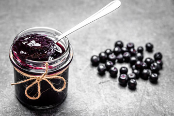 Aronia jam and fresh berry on stone table. - 783082745