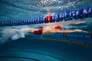 Muscular young man, swimmer in motion, preparing for competition, training in swimming pool...