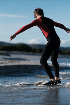 Junge Br&uuml;der im Neoprenanzug auf dem Skimboard am Strand auf Sardinien am Meer