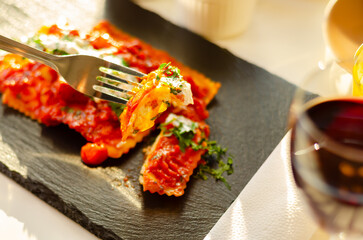 Four cheese filled ravioli in a tomato and basil sauce on the black stone plate - 783087937