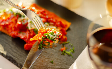 Four cheese filled ravioli in a tomato and basil sauce on the black stone plate - 783088164