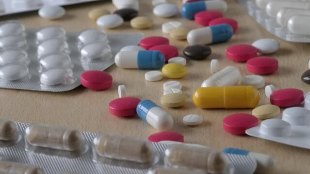 lot of multi-colored pills, capsules, vitamins, drugs, empty blisters on light wooden table, concept maintaining health, pharmaceutical market, medication treatment, deliberate drug overdose