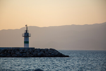 Lighthouse on the coast at sunset. Lighthouse in the harbour. Sunset over the sea and the...