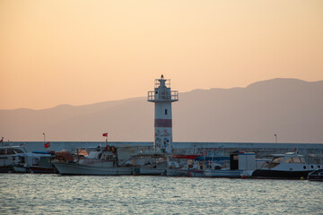 Lighthouse on the coast at sunset. Lighthouse in the harbour. Sunset over the sea and the lighthouse in the harbour.