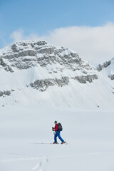 Fototapeta na wymiar A female skier stands at the snowy summit of a mountain, equipped with professional gear and skis, poised for an exhilarating descent.